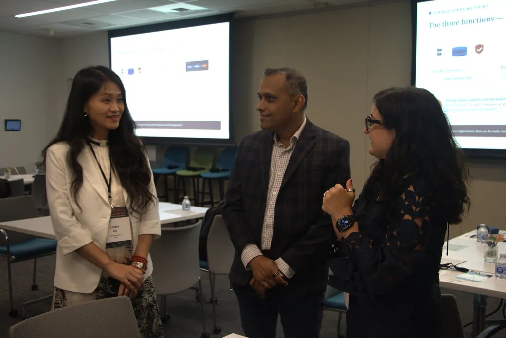 Three people talking in the room before the session begins.