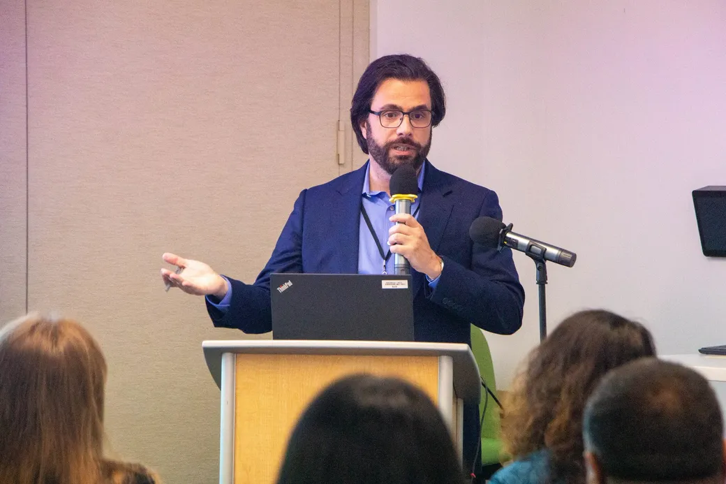 Dr. Roberto Araujo speaking at the lectern with a microphone.