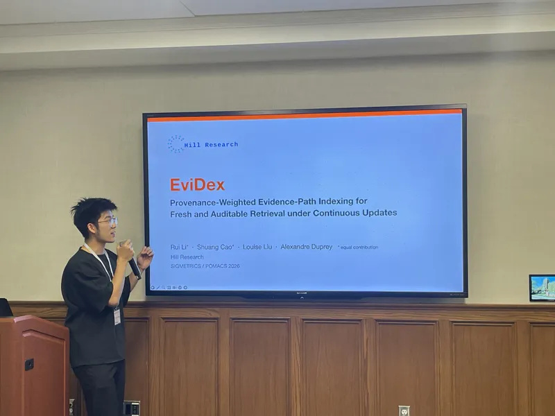 Kai Zheng of Hill Research presenting EviDex at ACM SIGMETRICS 2026 in Ann Arbor, beside the title slide